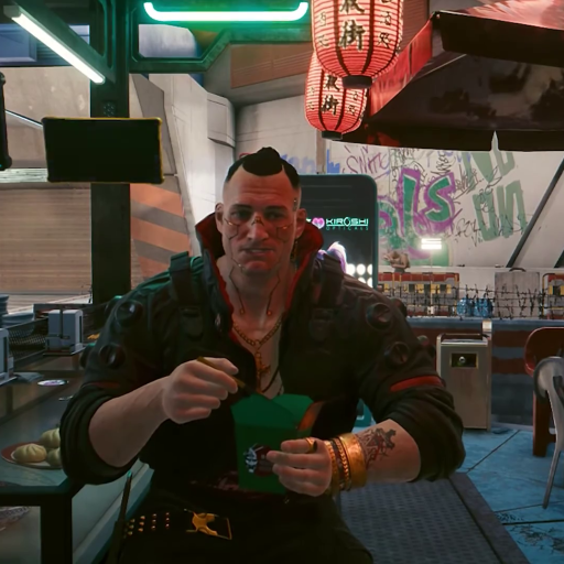 An image of a man with tattoo on his hands. a man sitting at a table with a green box in his hand. A man in a restaurant eating something